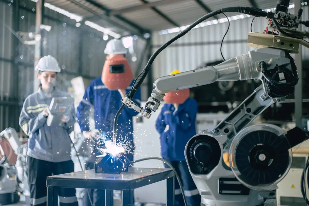 a robotic tool doing a welding task controlled by a team of engineers in a factory